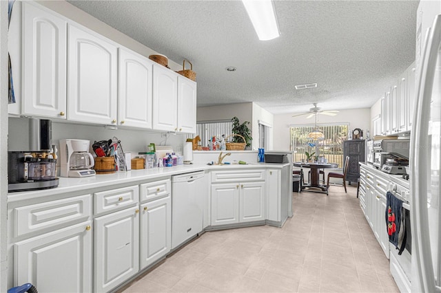 kitchen with white dishwasher, kitchen peninsula, white cabinetry, and sink