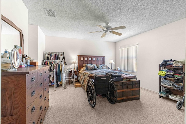 bedroom with ceiling fan, light colored carpet, and a textured ceiling