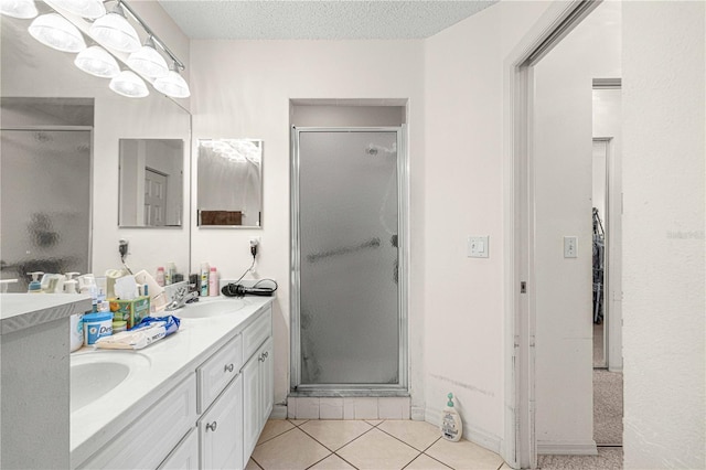 bathroom featuring tile patterned flooring, vanity, a shower with shower door, and a textured ceiling