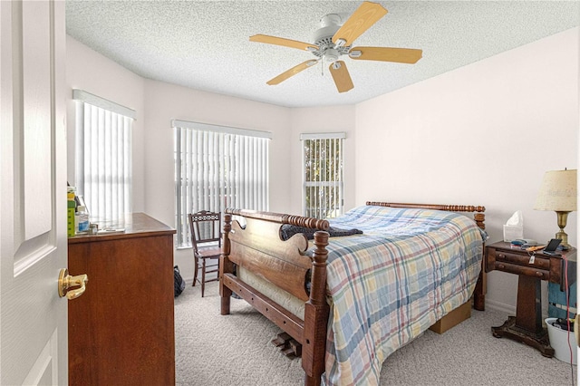 bedroom with ceiling fan, light colored carpet, and a textured ceiling