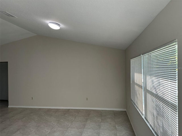 spare room with tile flooring, a textured ceiling, and lofted ceiling