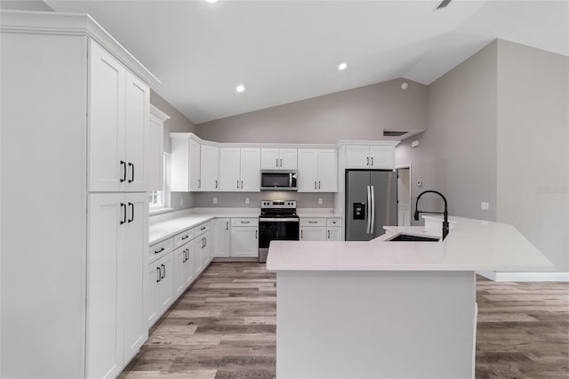 kitchen with white cabinetry, appliances with stainless steel finishes, vaulted ceiling, and light hardwood / wood-style floors