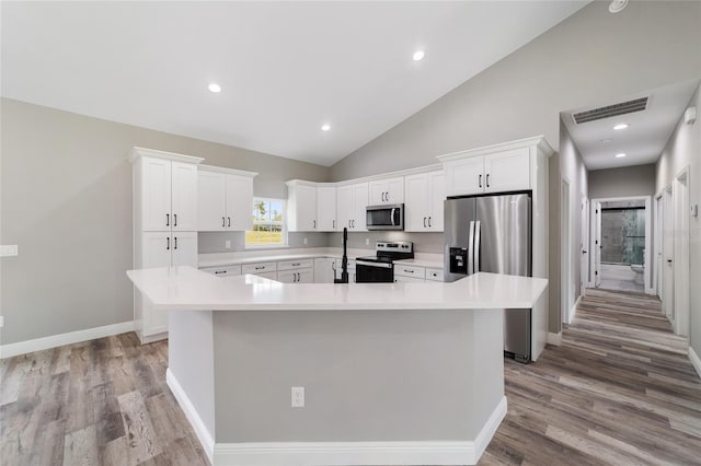 kitchen featuring white cabinets, appliances with stainless steel finishes, a center island, and light hardwood / wood-style flooring