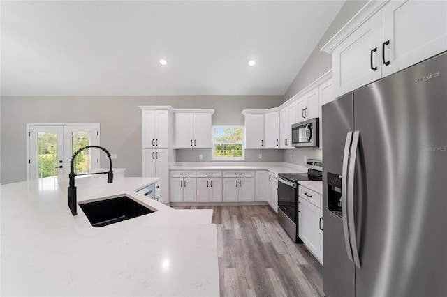 kitchen featuring a wealth of natural light, appliances with stainless steel finishes, lofted ceiling, and sink