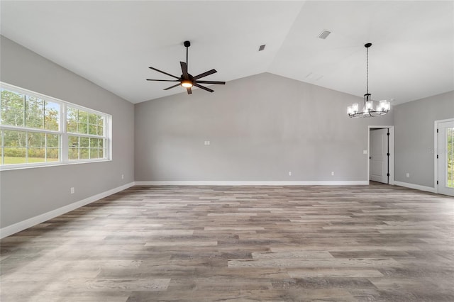 spare room with a wealth of natural light, vaulted ceiling, light hardwood / wood-style floors, and ceiling fan with notable chandelier