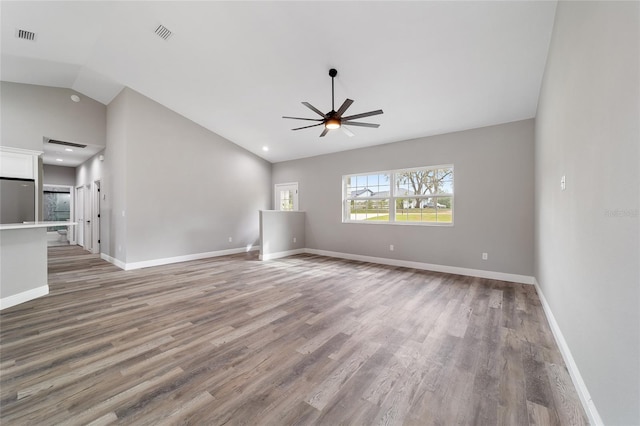 unfurnished living room with ceiling fan, wood-type flooring, and vaulted ceiling