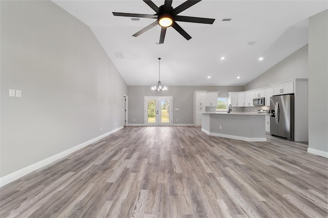 unfurnished living room with french doors, light hardwood / wood-style flooring, high vaulted ceiling, sink, and ceiling fan with notable chandelier