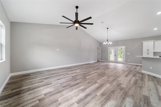 unfurnished living room featuring high vaulted ceiling, french doors, light hardwood / wood-style floors, and ceiling fan with notable chandelier