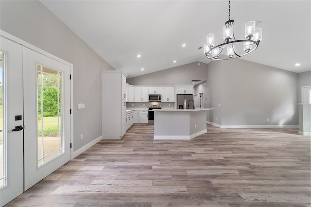 kitchen with appliances with stainless steel finishes, lofted ceiling, light hardwood / wood-style floors, and white cabinets