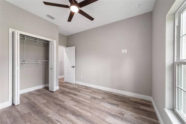 unfurnished bedroom featuring ceiling fan, multiple windows, a closet, and light wood-type flooring