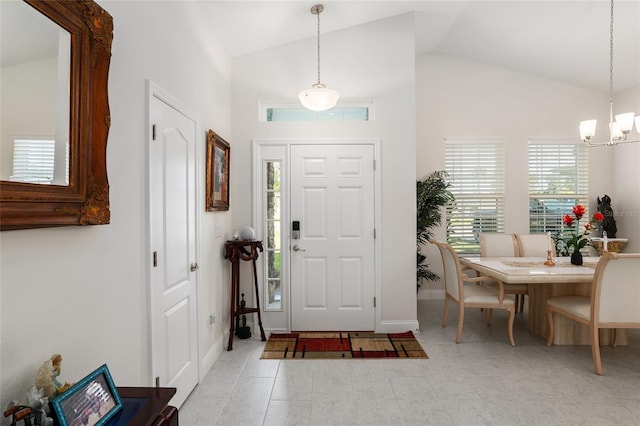 tiled entryway featuring high vaulted ceiling and a chandelier