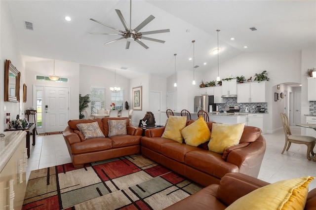 living room with light tile patterned flooring, ceiling fan with notable chandelier, and high vaulted ceiling