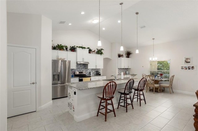 kitchen with a kitchen island with sink, lofted ceiling, a breakfast bar area, decorative backsplash, and appliances with stainless steel finishes