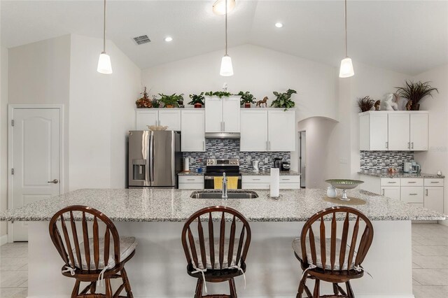 kitchen with tasteful backsplash, a kitchen island with sink, stainless steel appliances, and vaulted ceiling