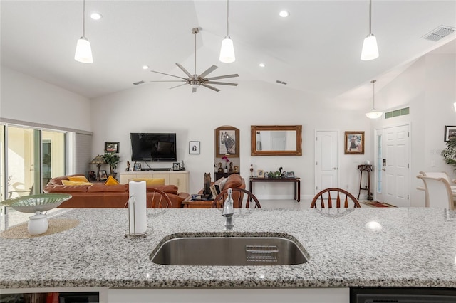 kitchen featuring light stone counters, sink, pendant lighting, and lofted ceiling