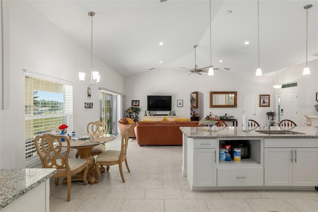 kitchen with high vaulted ceiling, white cabinets, ceiling fan with notable chandelier, decorative light fixtures, and light stone counters