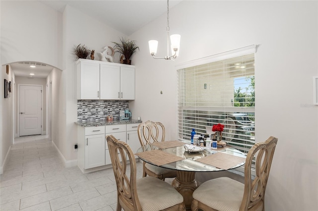 tiled dining space featuring high vaulted ceiling and a chandelier