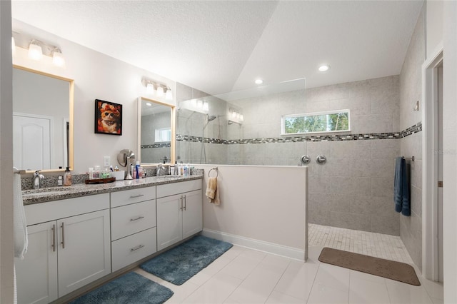 bathroom with tiled shower, a textured ceiling, vanity, and tile patterned floors