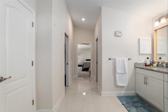 bathroom featuring tile patterned floors, vanity, vaulted ceiling, and a textured ceiling