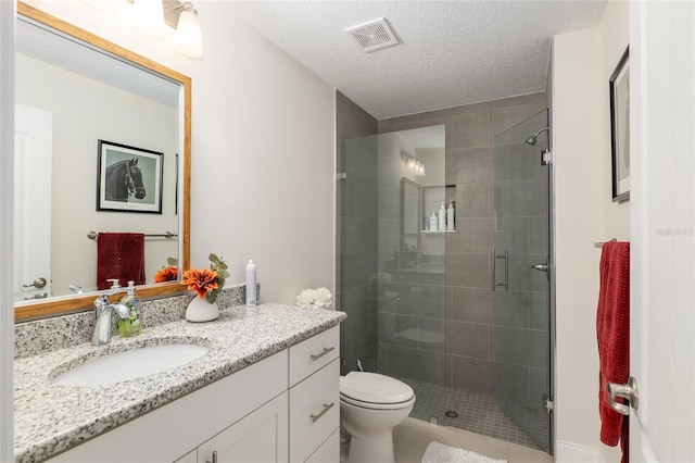 bathroom with vanity, toilet, an enclosed shower, and a textured ceiling