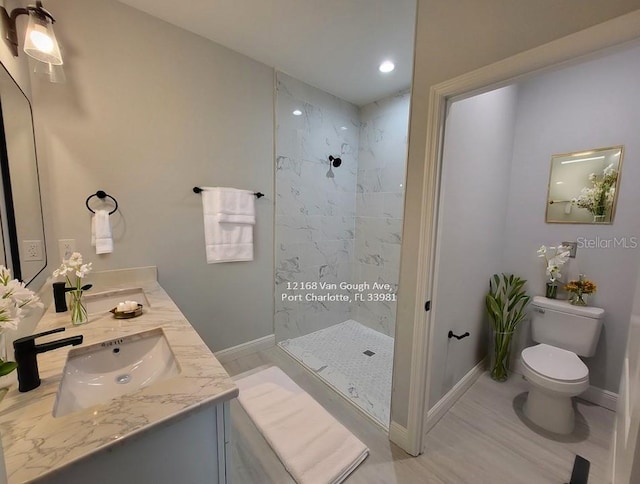 bathroom featuring vanity, toilet, and tiled shower