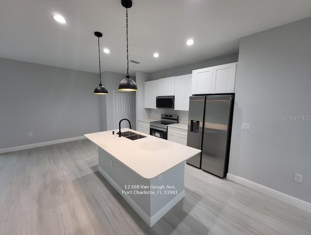 kitchen featuring white cabinetry, an island with sink, pendant lighting, appliances with stainless steel finishes, and light wood-type flooring