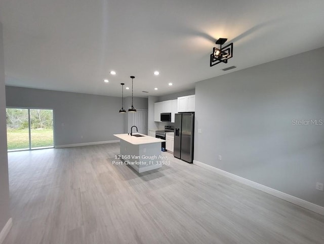 kitchen with light wood-type flooring, stainless steel appliances, a kitchen island with sink, white cabinets, and hanging light fixtures