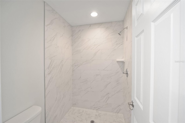 bathroom with a tile shower and toilet