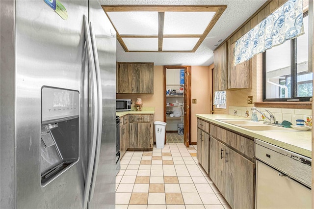 kitchen with a textured ceiling, light tile patterned flooring, sink, and appliances with stainless steel finishes