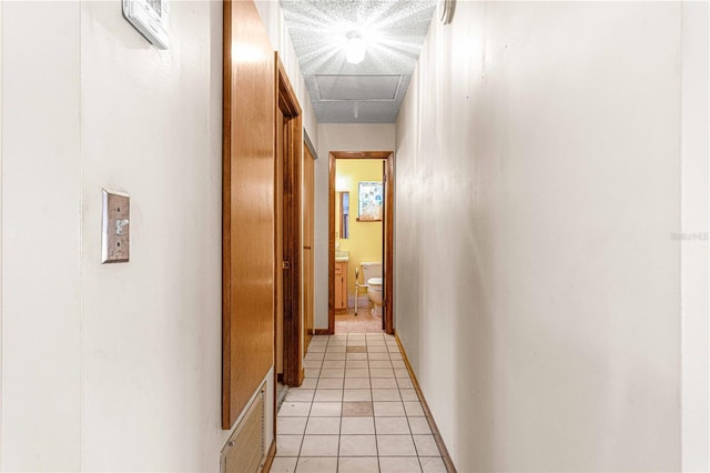 hallway featuring light tile patterned floors and a textured ceiling