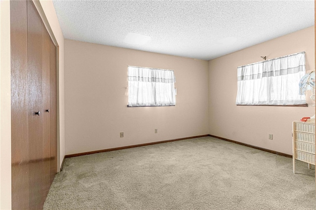 unfurnished bedroom with light carpet, a textured ceiling, and a closet