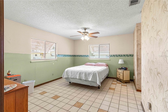 bedroom with multiple windows, light tile patterned floors, a textured ceiling, and ceiling fan