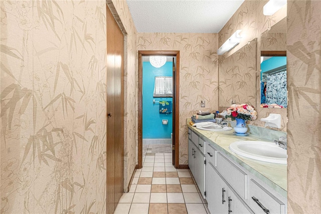 bathroom with tile patterned flooring, vanity, and a textured ceiling