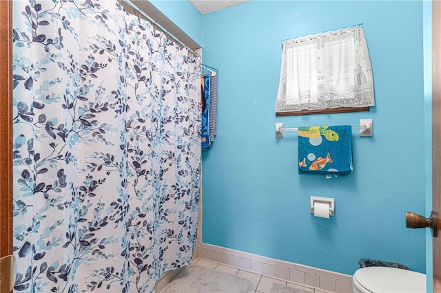 bathroom with tile patterned floors, toilet, a textured ceiling, and a shower with shower curtain