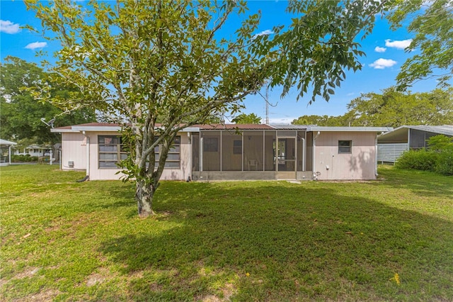 back of property with a sunroom and a yard