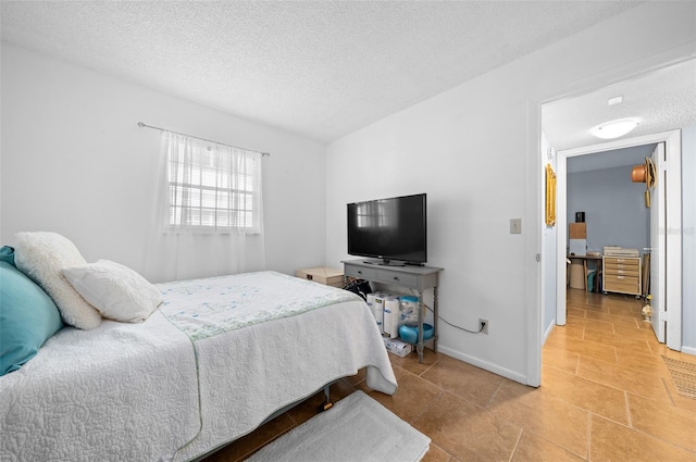 bedroom featuring light tile patterned floors, baseboards, and a textured ceiling