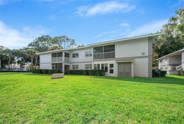 rear view of house with stucco siding and a yard