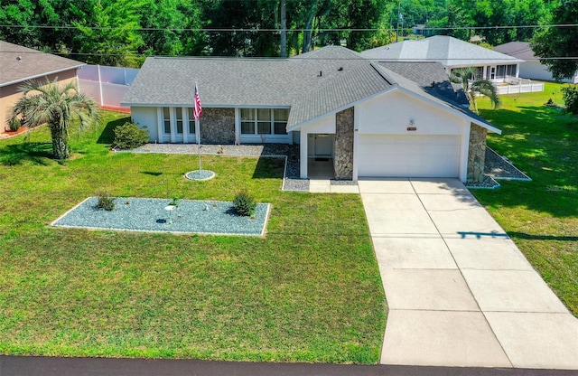 ranch-style house with a shingled roof, concrete driveway, stone siding, an attached garage, and a front yard