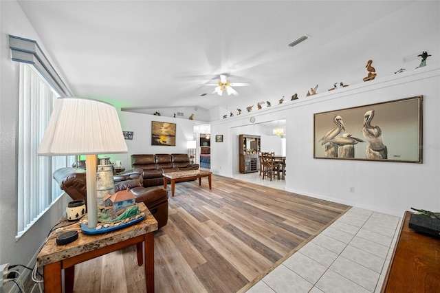 living area featuring lofted ceiling, wood finished floors, visible vents, and a ceiling fan