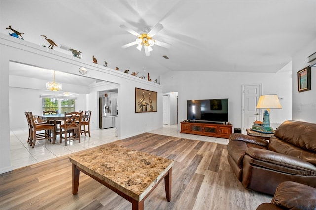 living room with light wood-type flooring, visible vents, vaulted ceiling, and ceiling fan with notable chandelier