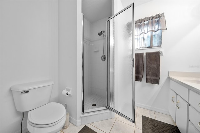 bathroom with toilet, a stall shower, vanity, baseboards, and tile patterned floors