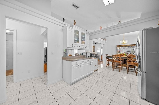 kitchen with light tile patterned floors, glass insert cabinets, freestanding refrigerator, and white cabinets