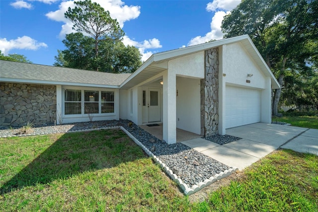 view of front facade featuring stucco siding, concrete driveway, a front yard, a garage, and stone siding