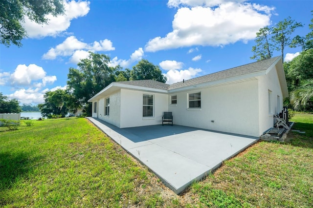 back of property with a patio, a yard, a shingled roof, and stucco siding