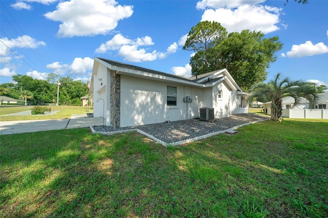 exterior space with central AC unit, a lawn, and stucco siding