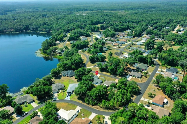 drone / aerial view featuring a water view, a wooded view, and a residential view