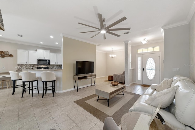 living room featuring ceiling fan with notable chandelier, light tile patterned flooring, crown molding, and decorative columns