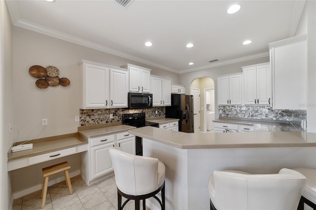 kitchen with a kitchen bar, kitchen peninsula, white cabinets, and black appliances