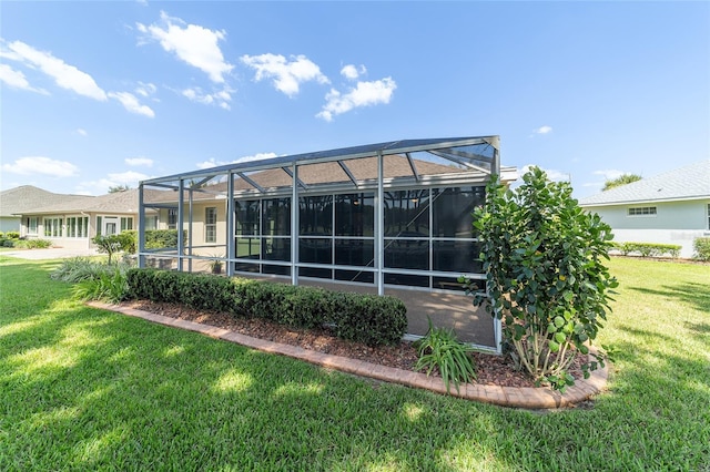 rear view of property featuring a lanai and a lawn