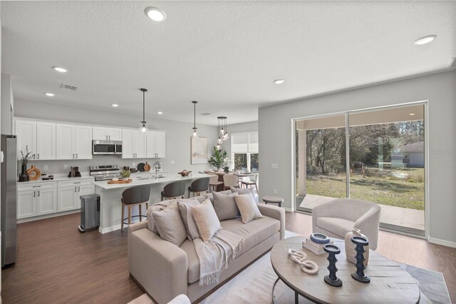 living room with a textured ceiling, dark wood-type flooring, and a wealth of natural light